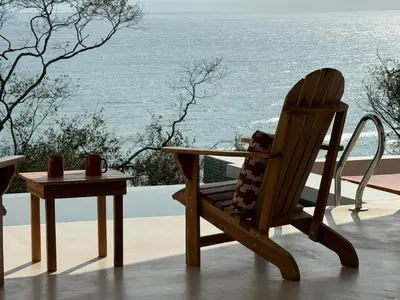 a wooden chair and a table with a view of the ocean at Les Roches - Paradise Retreat in Santa Teresa Beach