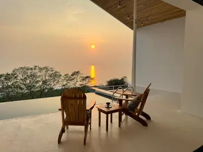 two chairs and a table on a balcony with the sunset at Les Roches - Paradise Retreat in Santa Teresa Beach