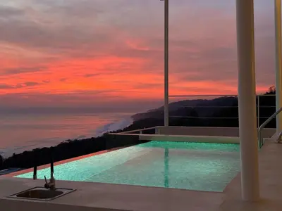 a swimming pool on top of a house with a sunset at Les Roches - Paradise Retreat in Santa Teresa Beach