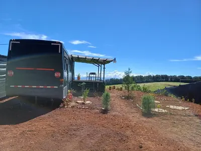 a bus parked in a dirt field with plants at BusHotel Poás con Jacuzzi y Chimenea in Fraijanes