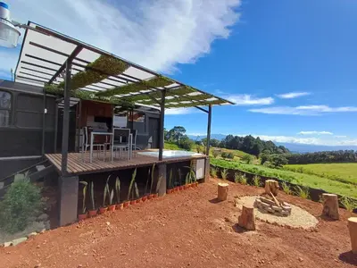 a black house with a deck with a view at BusHotel Poás con Jacuzzi y Chimenea in Fraijanes