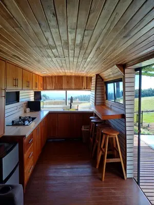 a kitchen with wooden cabinets and a large window at BusHotel Poás con Jacuzzi y Chimenea in Fraijanes