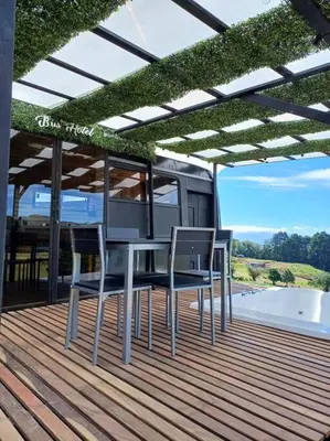 a table and chairs on a deck with a roof at BusHotel Poás con Jacuzzi y Chimenea in Fraijanes