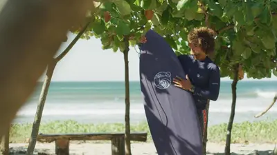 a boy standing on the beach holding a surfboard at Silvestre Nosara Hotel & Residences in Nosara