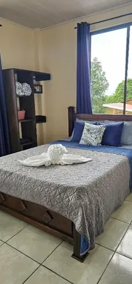 a bed in a bedroom with a large window at Arenal Paradise Lodge in Fortuna