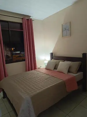 a bedroom with a bed with red curtains and a window at Arenal Paradise Lodge in Fortuna