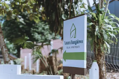a sign in front of a fence with trees at Natura Bungalows in Fortuna
