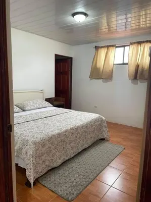 a bedroom with a bed and two windows at Hermoso apartamento en Quepos/ Manuel Antonio. in Quepos