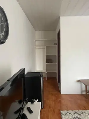 a room with a desk with a tv and a clock at Estudio como en casa in Quepos