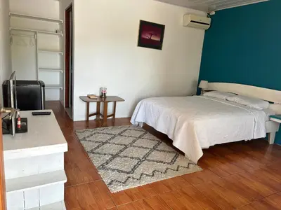 a bedroom with a bed and a table and a tv at Estudio como en casa in Quepos