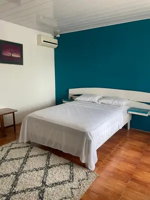 a bedroom with a bed with a blue wall at Estudio como en casa in Quepos