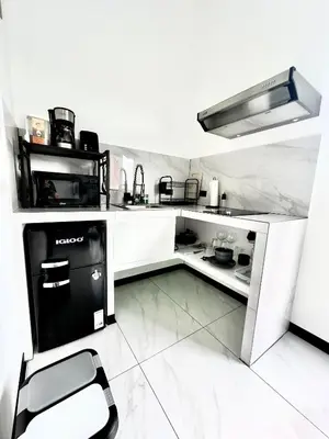 a small white kitchen with a stove and a chair at Black & White Apartments in Monteverde Costa Rica