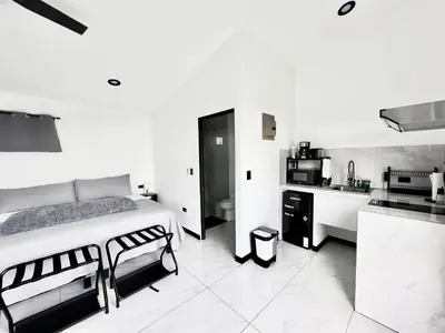 a black and white bedroom with a bed and a kitchen at Black & White Apartments in Monteverde Costa Rica