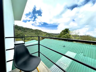 a black chair sitting on a balcony with a swimming pool at Black & White Apartments in Monteverde Costa Rica