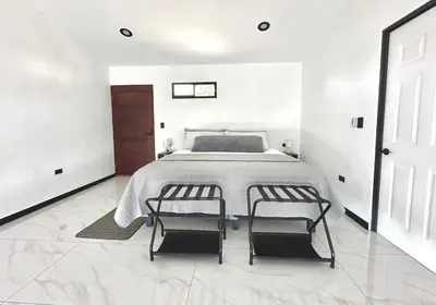 a white bedroom with a bed and two chairs at Black & White Apartments in Monteverde Costa Rica