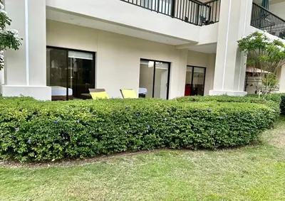 a hedge in front of a building with two chairs at Private Modern Condo by Jac Beach in Jacó