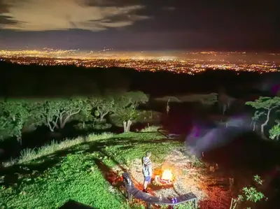 a man standing in front of a fire at night at Bus Hotel with HotTube in the middle of mountain in Sarchí