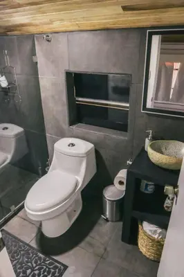 a bathroom with a white toilet and a sink at Bus Hotel with HotTube in the middle of mountain in Sarchí
