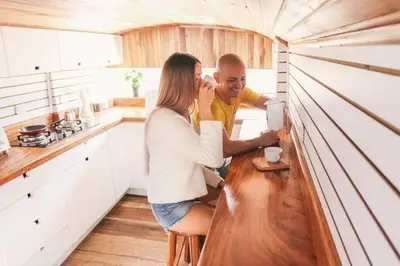 a man and a woman sitting at a counter in a kitchen at Bus Hotel with HotTube in the middle of mountain in Sarchí