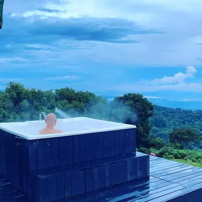 a bath tub with a man sitting in it at Bus Hotel with HotTube in the middle of mountain in Sarchí