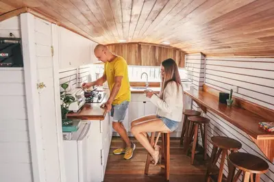 a man and a woman in a tiny house kitchen at Bus Hotel with HotTube in the middle of mountain in Sarchí
