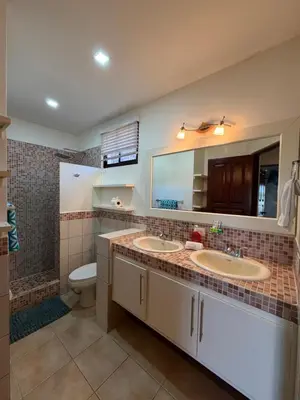 a bathroom with two sinks and a toilet and a mirror at Peaceful Bliss Condo inside a 6 pool Complex in Coco