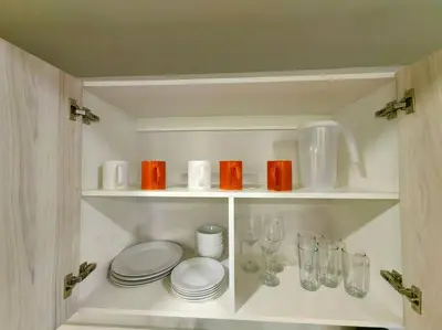 a white cabinet with plates and glasses on it at 906A URBN Barrio Escalante Estudio con A/C y Parqueo in San José