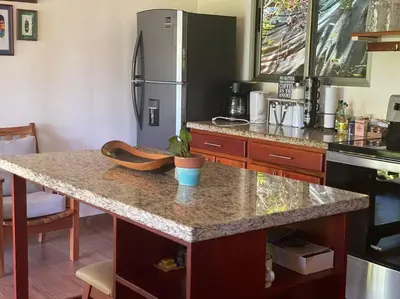 a kitchen with a granite counter top with a refrigerator at Casita Colibri–Mile to the Beach–Cable&Fiber Wifi! in Uvita