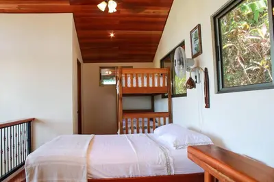 a bedroom with a bed and a staircase in a house at Casita Colibri–Mile to the Beach–Cable&Fiber Wifi! in Uvita
