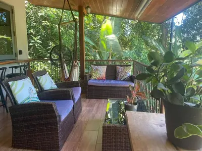 a porch with wicker chairs and a table and plants at Casita Colibri–Mile to the Beach–Cable&Fiber Wifi! in Uvita