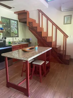 a kitchen with a table with a counter and a staircase at Casita Colibri–Mile to the Beach–Cable&Fiber Wifi! in Uvita