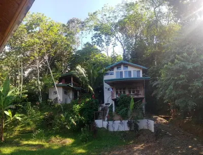 a white house in the middle of a forest at Casita Colibri–Mile to the Beach–Cable&Fiber Wifi! in Uvita