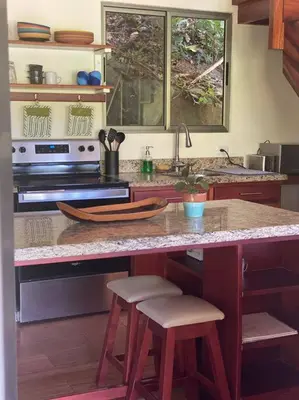 a kitchen with a counter with stools and a counter top at Casita Colibri–Mile to the Beach–Cable&Fiber Wifi! in Uvita