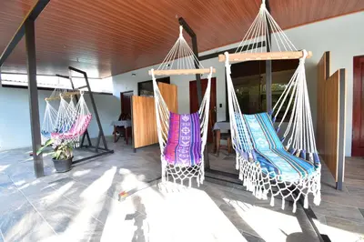 two hanging hammocks in a room with a table at Raya in Matapalo