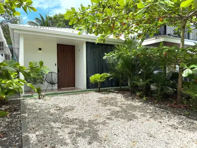 a white house with a black door and trees at Villa El Bosque Dorado in Fortuna