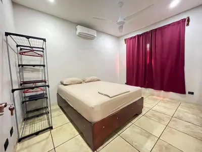 a bedroom with a bed with a ladder and a red curtain at Casa Bella Vista in Quepos