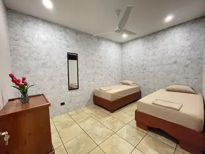a room with two beds and a table and a mirror at Casa Bella Vista in Quepos