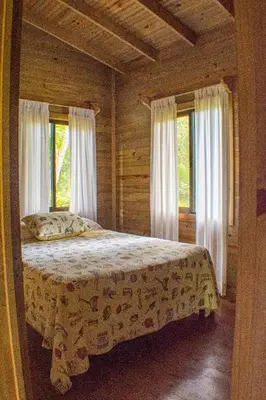 a bedroom with a bed in a room with windows at CASITAS GINGER in Quepos