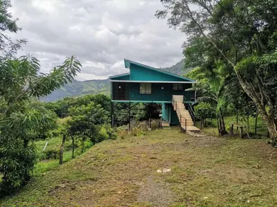 a green house on a hill with trees at Casa Sios San Luis, Monteverde in Monteverde Costa Rica