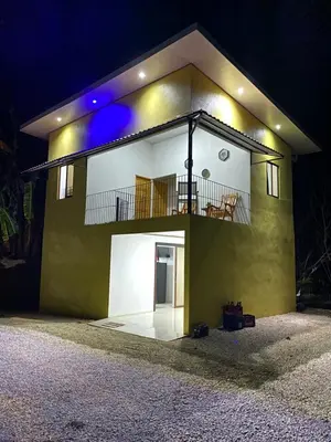 a small yellow house with a balcony at night at Casa Zion in San Juanillo