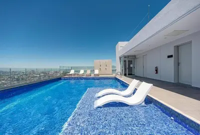a swimming pool with two white chairs on a building at 0404 iFreses estudio con Aire Acondicionado y Parqueo in Curridabat