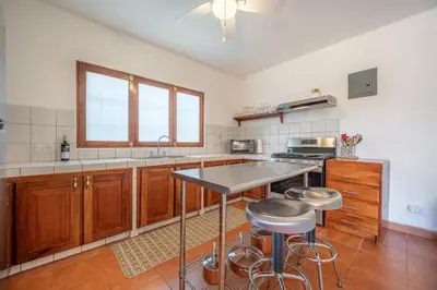 a kitchen with a counter and stools in it at Casa Palma Real in Playa Junquillal