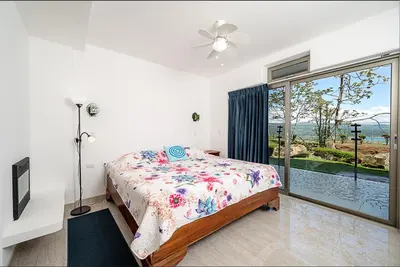 a bedroom with a bed and a large window at Lake Arenal Condos in Naranjos Agrios