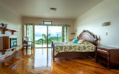 a bedroom with a bed and a large window at Lake Arenal Condos in Naranjos Agrios