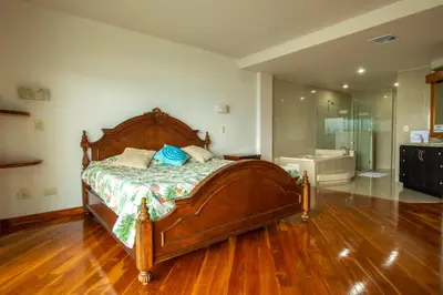 a bedroom with a large wooden bed and a bathroom at Lake Arenal Condos in Naranjos Agrios