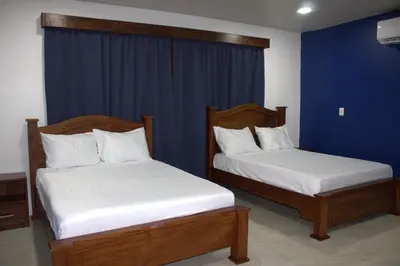 two beds in a room with blue walls and blue curtains at Home La Fortuna in Fortuna