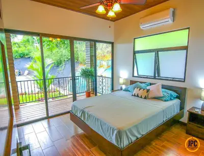 a bedroom with a large bed and a balcony at Modern Mountain View Home by Nauyaca Waterfall in Platanillo
