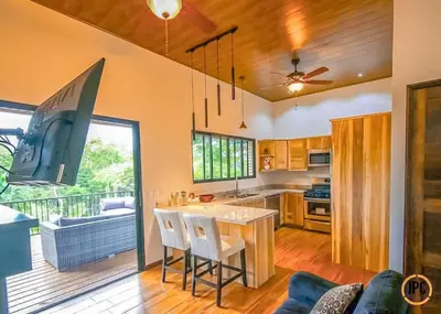a kitchen with a bar with a view of a balcony at Modern Mountain View Home by Nauyaca Waterfall in Platanillo