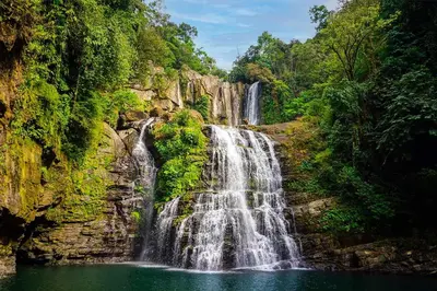 a waterfall in the middle of a forest at Modern Mountain View Home by Nauyaca Waterfall in Platanillo