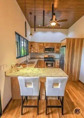 a kitchen with a large island with white chairs at Modern Mountain View Home by Nauyaca Waterfall in Platanillo